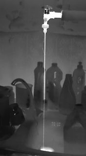 Wasserstrahl aus einem Wasserhahn über Flaschen