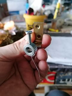 Hand hält Metallklemmung mit Schraube und Draht