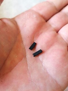 Zwei kleine schwarze Bauteile in einer Handfläche