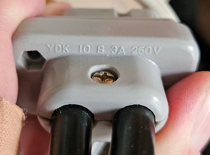 Nahaufnahme eines grauen Netzsteckers mit Beschriftung