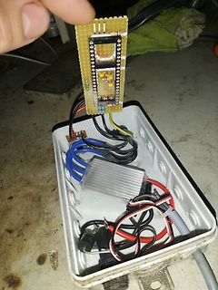 Hand hält Leiterplatte über Gehäuse mit Elektronikkomponenten