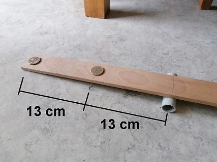 Holzleiste mit Maßangaben und Münzen