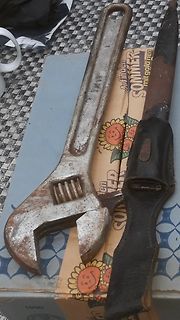 Schraubenschlüssel und Messer in Scheide auf Karton