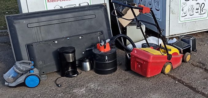 Elektroaltgeräte vor einer Entsorgungsstelle