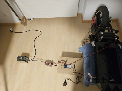 Elektronikaufbau mit Mikrocontroller und E-Bike-Rad auf Holzboden