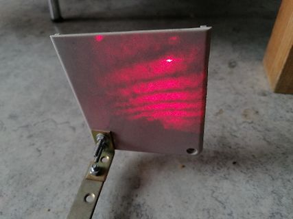 Reflexion eines roten Laserstrahls auf einer Metallplatte