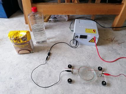Versuchsaufbau mit Netzgerät und Wasserbehälter