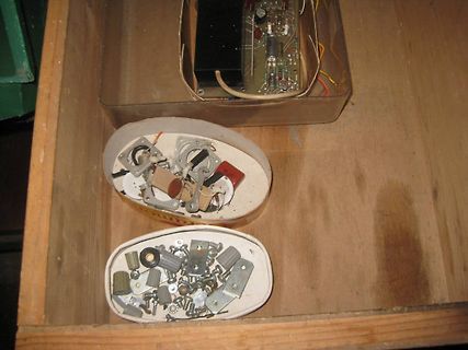 Elektronikbauteile und Kleinteile in Schachteln auf Holzuntergrund