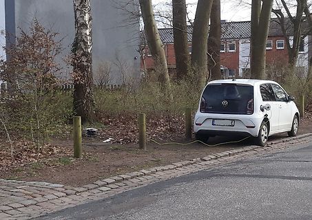 Weißer VW Up an einer Ladestation