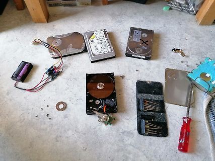 Werkzeug und zerlegte Festplatten auf Boden