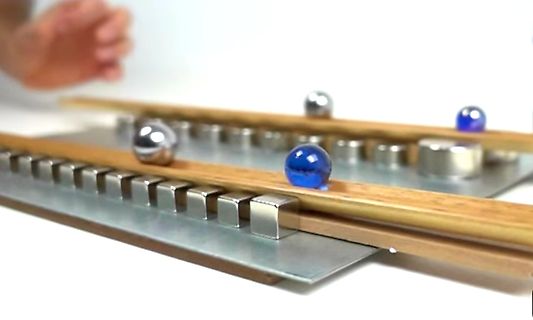 Kugellager-Aufbau mit Metallkugeln und blauen Glasmurmeln