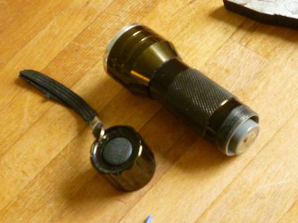 Taschenlampe und Batteriefach auf Holzuntergrund