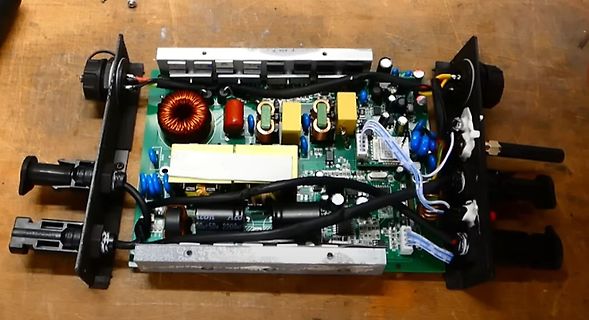 Offene Elektronikplatine eines Netzteils auf Holztisch