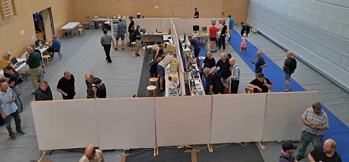 Menschen an Messplätzen in einer Messehalle