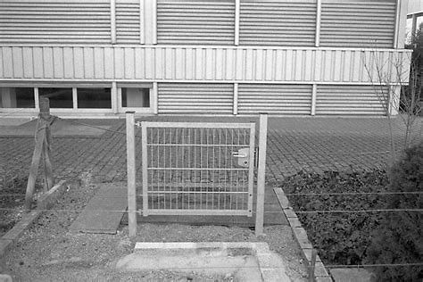 Außenansicht eines Gebäudes mit Lamellenfassade und Zaun
