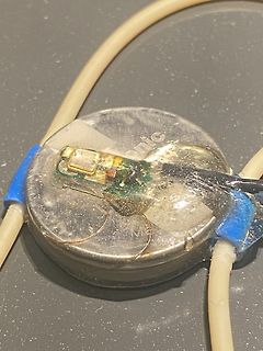 Knopfzellenbatterie mit aufgeklebter kleiner Platine und Kabeln