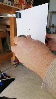 Hand hält weißes Papier vor Werkstatt-Hintergrund