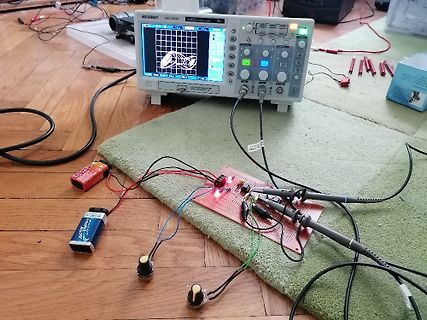 Elektronik-Versuchsaufbau mit Oszilloskop, Breadboard und Batterien