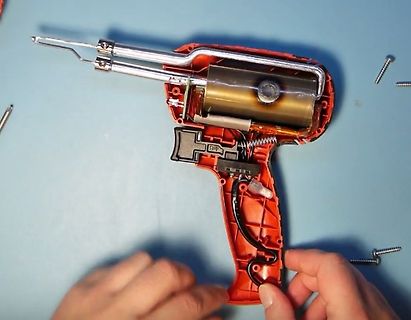 Zerlegtes Heißklebegewehr auf blauem Untergrund