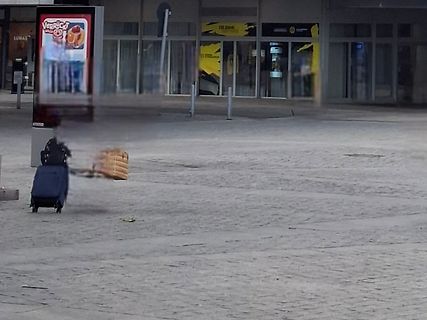 Person mit Koffer vor einem Gebäude