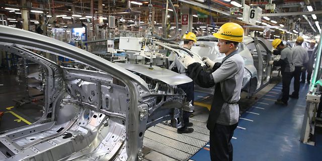 Arbeiter in einer Automobilfertigung an einem Autogestell