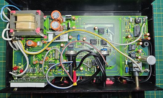 Geöffnete Elektronikplatine mit Transformator und Bauteilen