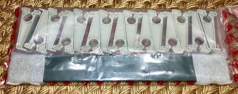 Plastikhalterungen und Metallleiste in Plastikverpackung