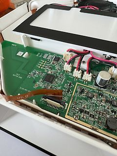Geöffnete Elektronik mit grüner Leiterplatte und Kabeln