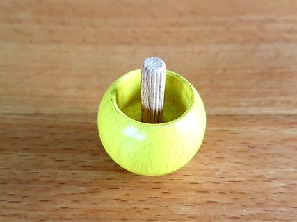 Gelber Holztopf mit Holzstab auf Holztisch