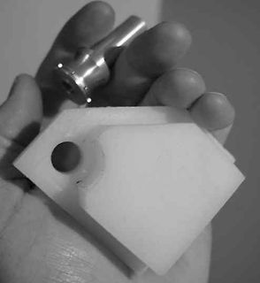 Metallbauteil in einer Hand mit weißem Kunststoffteil