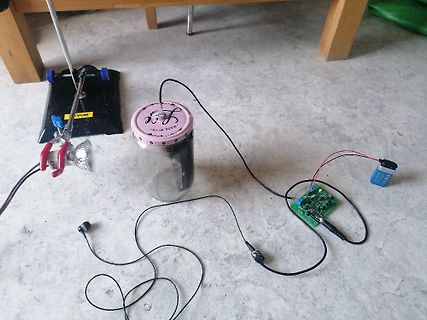 Elektronischer Aufbau mit Glasgefäß, Leiterplatte und Batterie