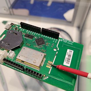 Grüne Leiterplatte mit Microchip-Bauteil und Messspitze
