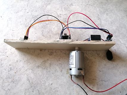 Elektronikaufbau mit Motor und Kabeln auf Holzbrett