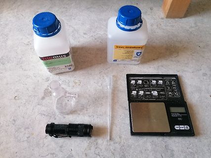 Chemikalien, Glasgefäß, Waage und Taschenlampe auf Tisch
