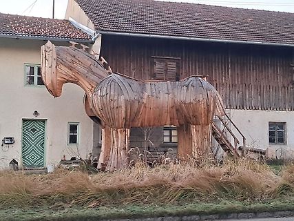 Holzskulptur eines Pferdes vor einem Haus