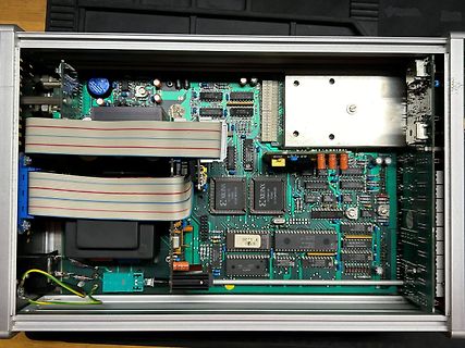 Innenansicht eines elektronischen Geräts mit Leiterplatte und Flachbandkabeln