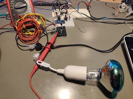 Elektronik-Versuchsaufbau mit Multimeter, Breadboard und Glühbirne