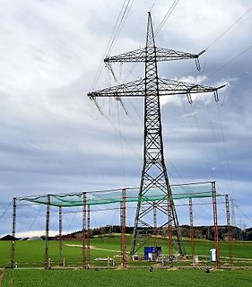 Hochspannungsmast und Feld mit Schutznetz