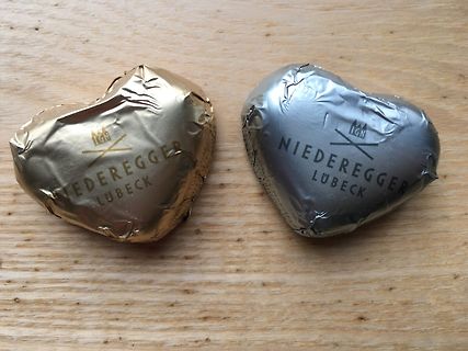 Zwei herzförmige Pralinen in Gold- und Silberfolie