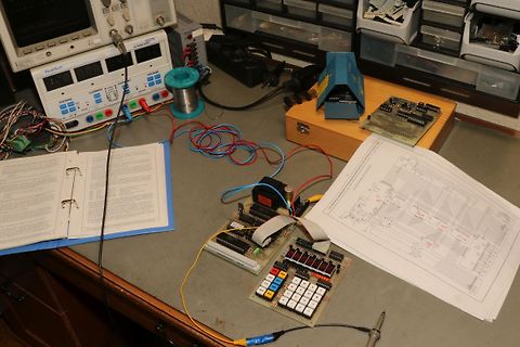 Elektronik-Arbeitsplatz mit Oszilloskop, Leiterplatte und Schaltplan