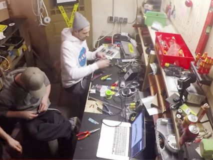 Zwei Personen in einer Werkstatt an einem Arbeitstisch