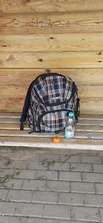 Rucksack, Wasserflasche und Orange auf Holzbrett
