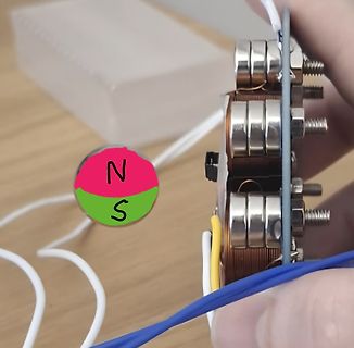 Nahaufnahme eines elektromagnetischen Bauteils mit Polmarkierung