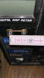 Nahaufnahme eines digitalen Amperemeters mit Maßband