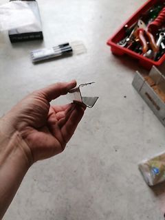 Hand hält ein gebogenes Metallteil in einer Werkstatt
