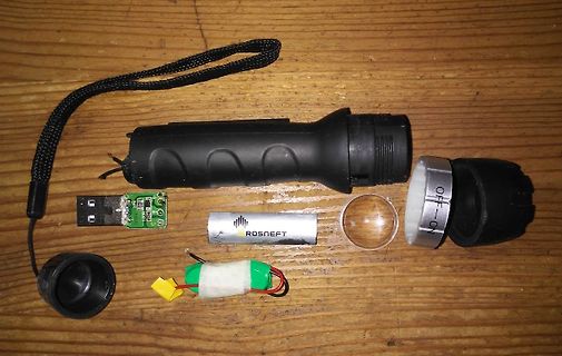 Zerlegte Taschenlampe mit Komponenten auf Holzuntergrund