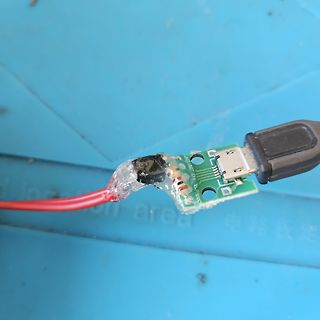 Defekter USB-Adapter mit Klebeband und rotem Kabel