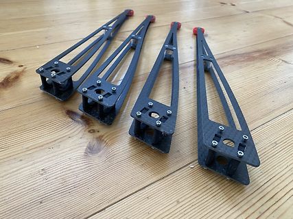 Vier Carbon-Bauteile auf Holzuntergrund