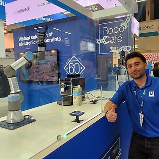 Mann an Messestand mit Roboterarm