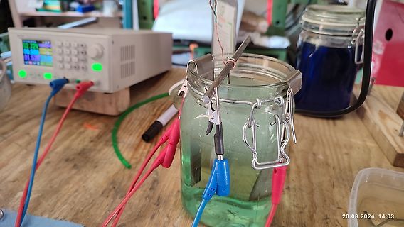 Versuchsaufbau mit Labornetzteil und Glasgefäß